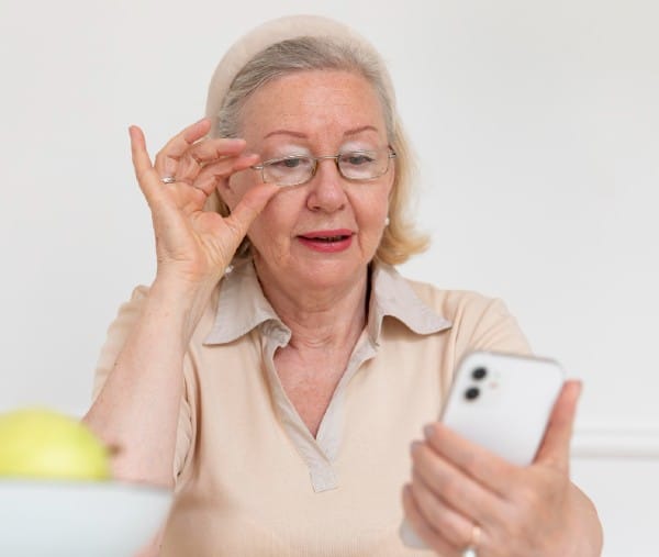 Senior woman having difficulties reading her phone due to cloudy vision possibly from cataracts.